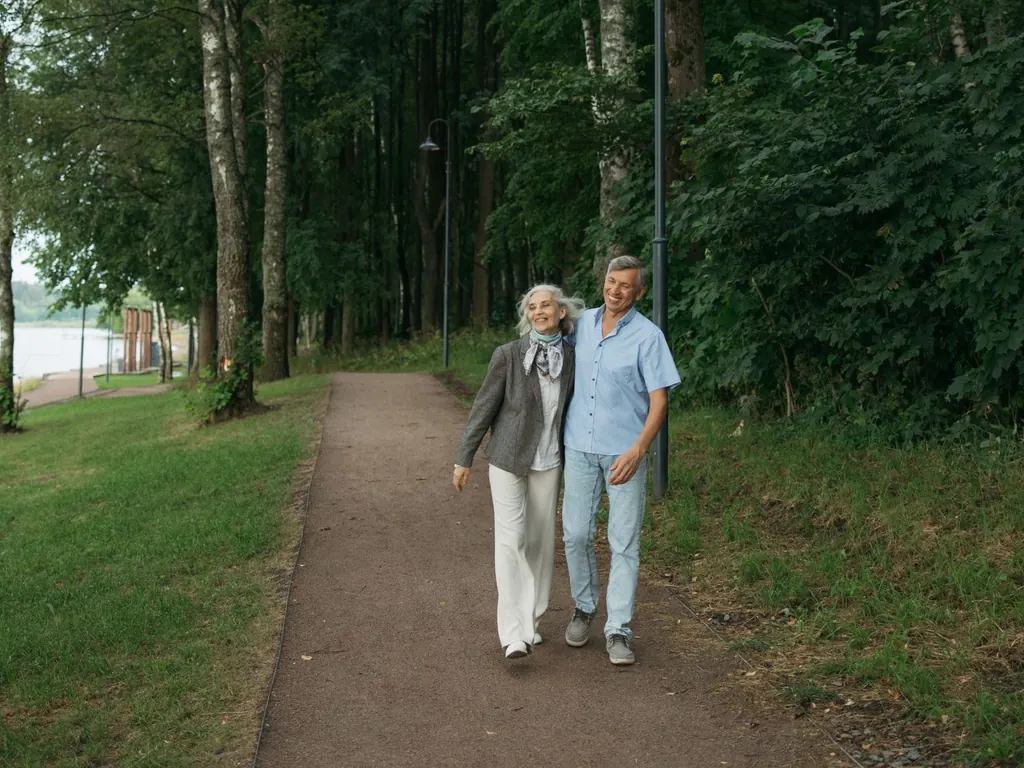 Older couple walking a tree-lined path, funding retirement with a drawdown lifetime mortgage